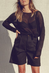 A semi sheer long sleeve black knitted top styled with the hem knotted for spring and summer styling