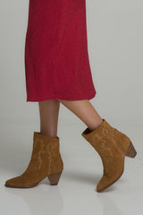 A model wearing brown suede cowboy boots