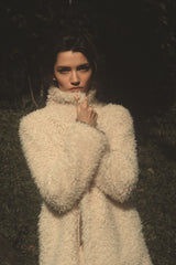 Model wears soft faux fur jacket in cream colour by LILYA