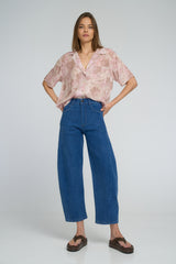 Woman wearing a pink floral blouse and blue jeans by LILYA Australia