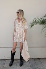 Woman wearing babydoll style drop waist mini dress with button frnt detail and a knitted jumper