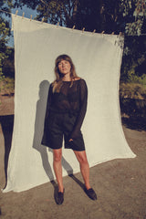 A woman wearing an all-black outfit with the Opaline knit top and black m=bermuda shorts by LILYA.