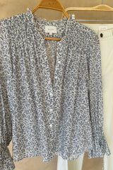 Rack photo of beautiful blouse with shirred shoulder detail and frill neckline.