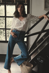 Model wears mid blue vintage look denim jeans with pocket detail and white blouse on weekend away