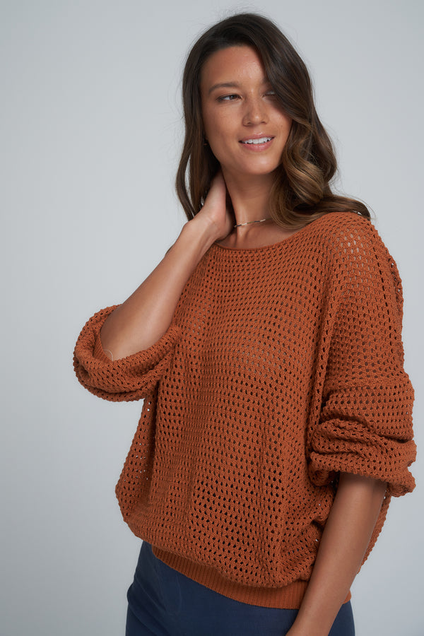 A model wearing a rust coloured knit jumper in Australia