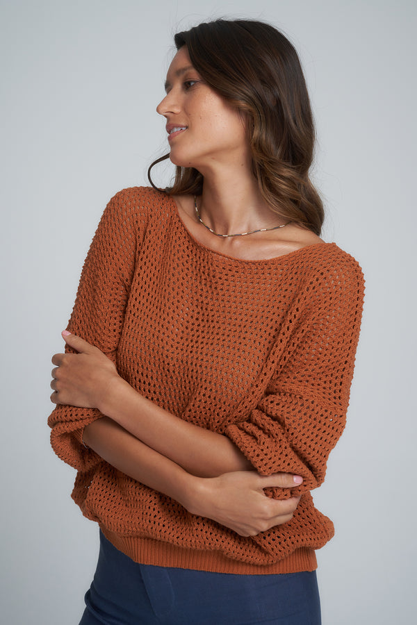 A woman wearing a rust coloured cotton knit jumper