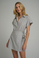 A woman wearing a black and white cotton mini wrap dress