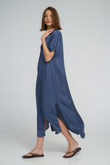 Model wearing LILYA Hutton Dress in shimmering ocean blue fabric with button-through front and side splits