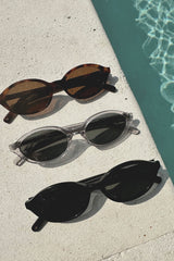 Three pairs of sunglasses on a concrete surface near a pool.