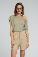 Woman wearing a green off-shoulder top and beige shorts