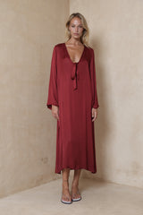 Model wears long flared sleeve satin viscose dress in merlot red