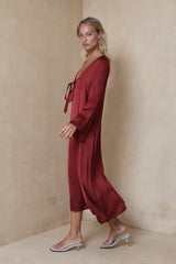 Side view of a woman in a flowing red silky satin dress