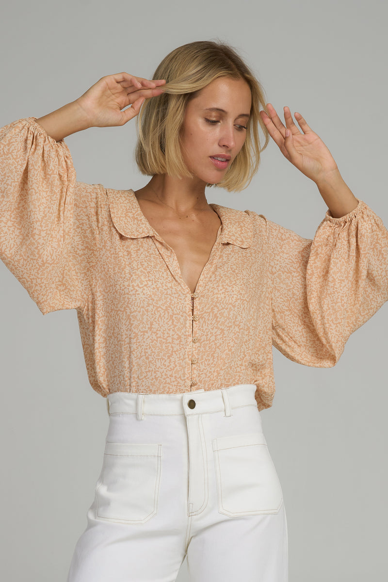 A model wearing a yellow floral long sleeve blouse