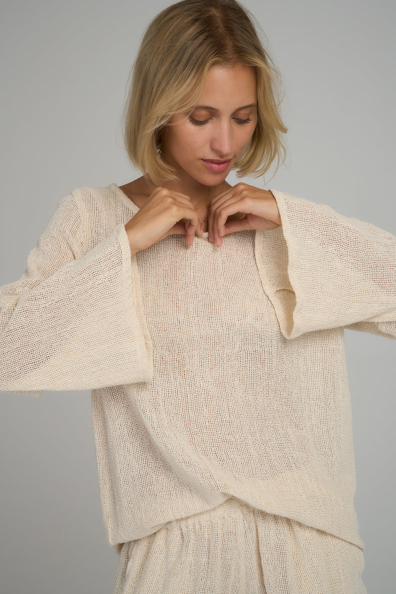 A model wearing a natural cotton mesh long sleeve blouse