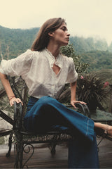 Model wears embroidered white blouse with button front and lace trim