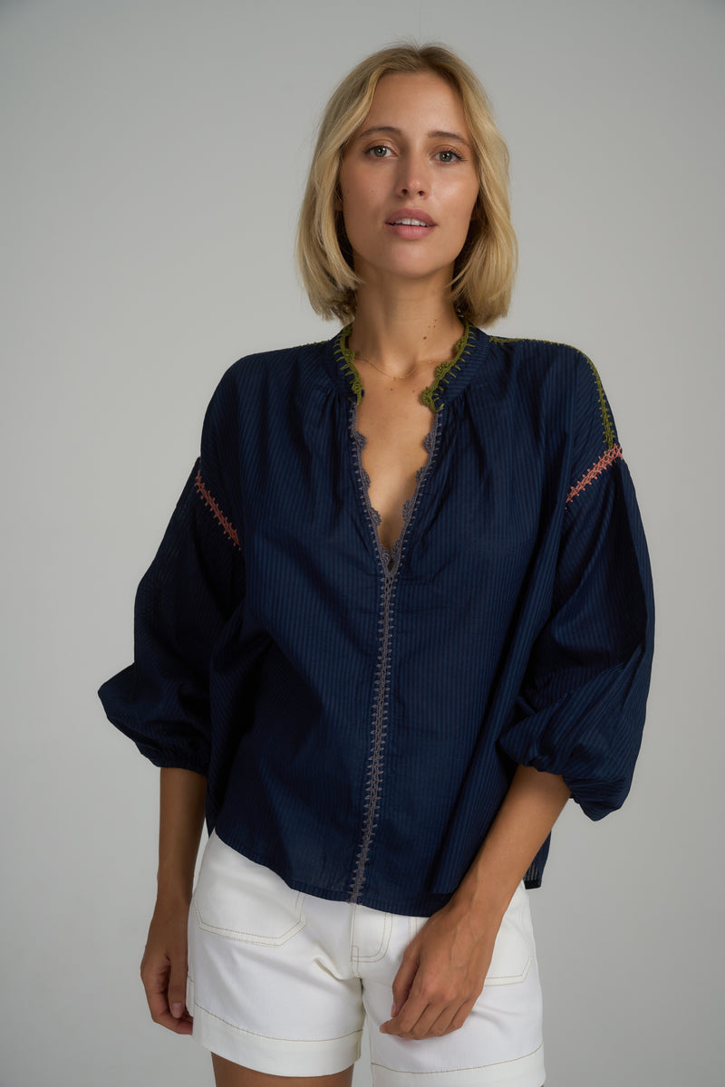 A model wearing a navy cotton top with crochet trim