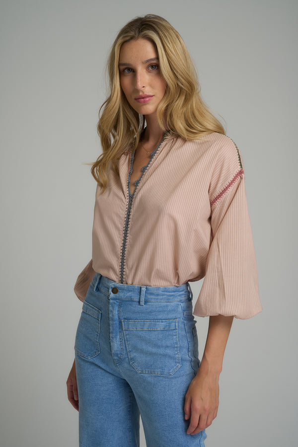 A woman wearing a cotton pink stripe long sleeve blouse