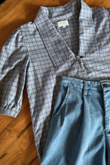 Flat lay of blue check shirt with short puff sleeves