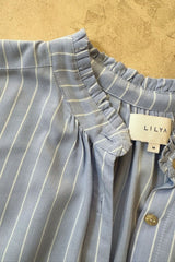Close-up of a blue striped shirt with button front and neck frill detail