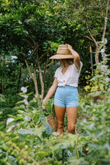 Jess in her garden wearing the chamomile denim shorts perfect for everyday wear in stretch cotton. 