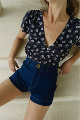 Model wears the high-waisted dark denim shorts in stretch cotton