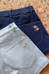 Flat lay of the two colours of denim shorts in the LILYA X JKB collaboration. 
