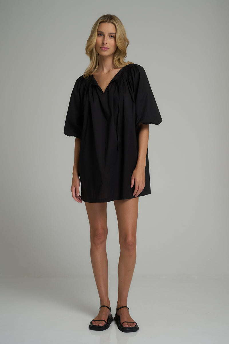 A model wearing a casual black cotton mini dress