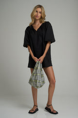 A woman wearing a casual black cotton mini dress for the beach