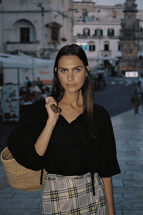 A model wearing a classic black cotton top with balloon sleeves