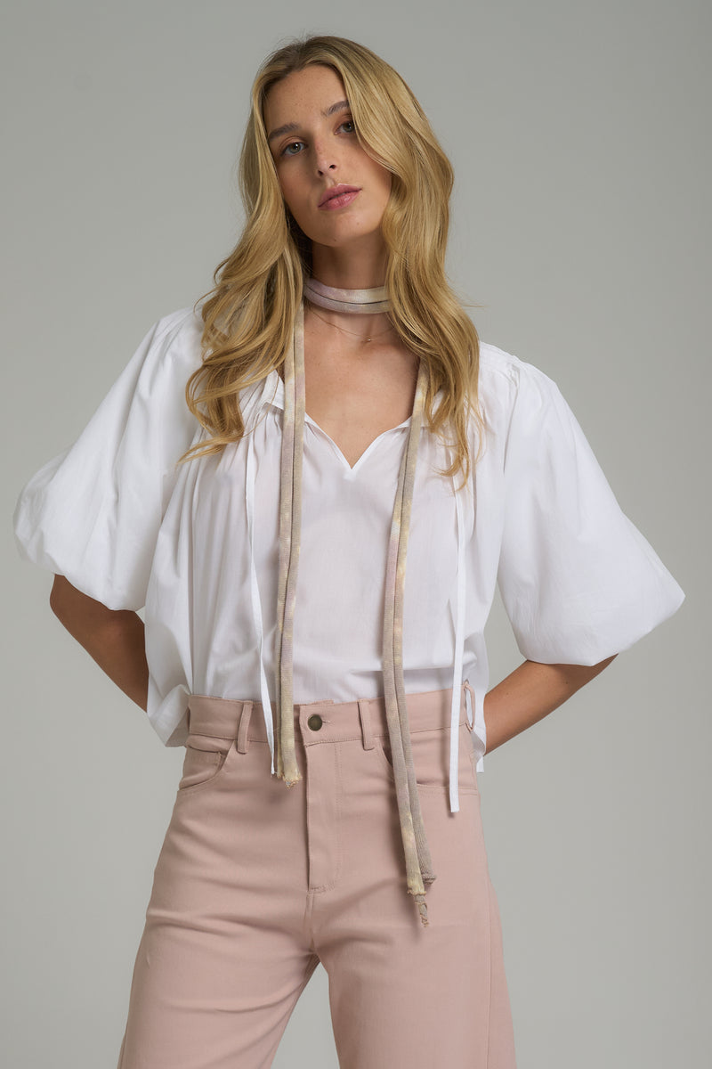 A model wearing a white cotton blouse with tie details