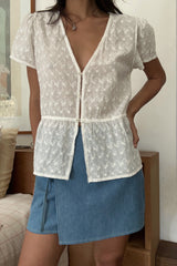 Model wears a wrap mini skirt with tie-side detail styled with a white embroidery top by LILYA