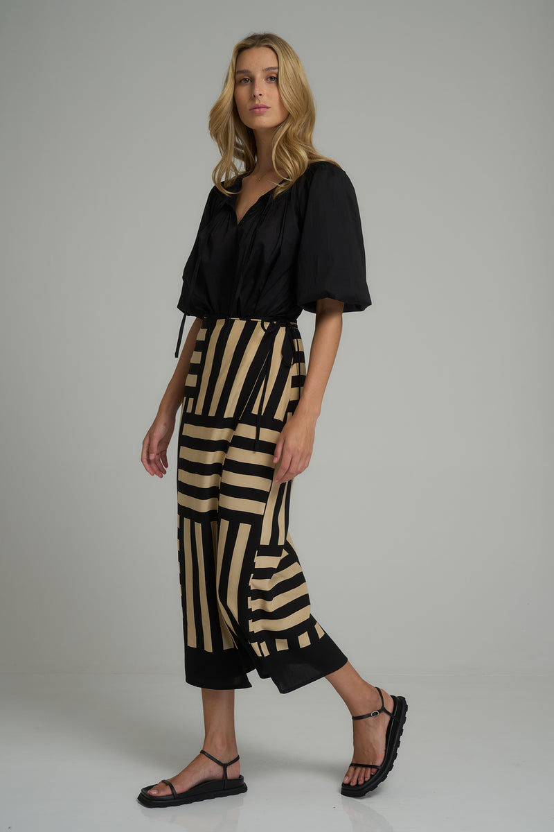 A woman wearing a black and creme maxi wrap skirt