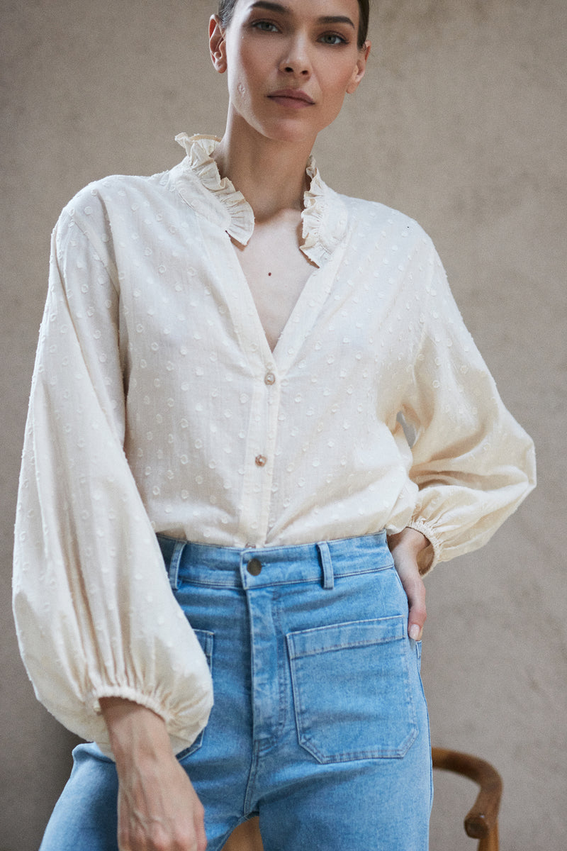 A woman wearing a feminine creme coloured blouse