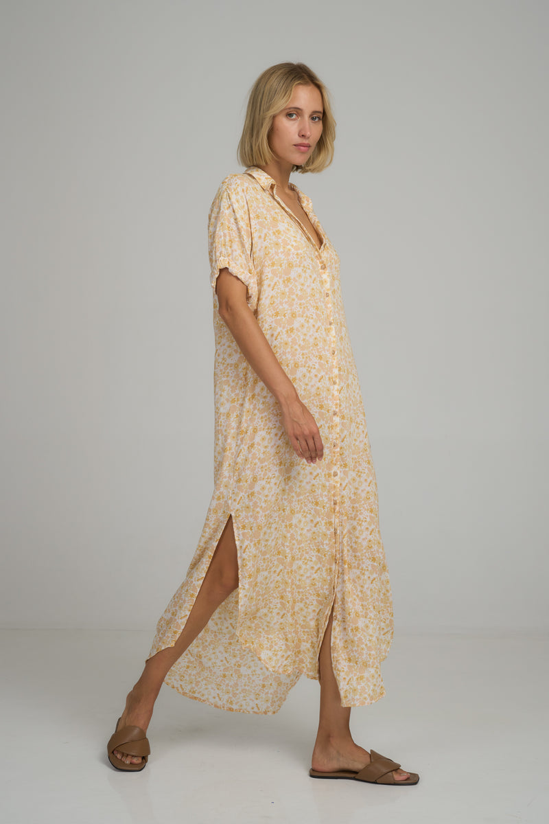 A woman wearing a casual yellow floral maxi shirt dress