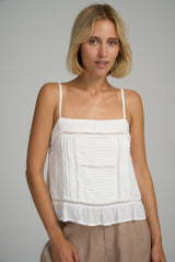 A woman wearing a feminine white summer top