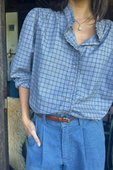 Model wears check shirt with button front and frill detail, styled with jeans for a casual look