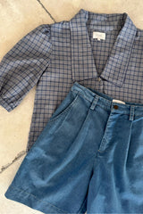 Flat lay of plaid preppy shirt with bermuda shorts