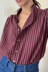 Close up photo of a button-up stripe shirt with frill detail on the neck.