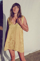 Olivia wearing the satin yellow jacquard mini dress with a deep v neckline for summer events