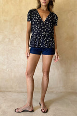 Model wearing the relaxed fit Monty Top in a floral yarrow print with a peplum and button front. 