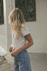 A woman wearing a white button-front blouse with lightly puffed sleeves perfect for summer days.
