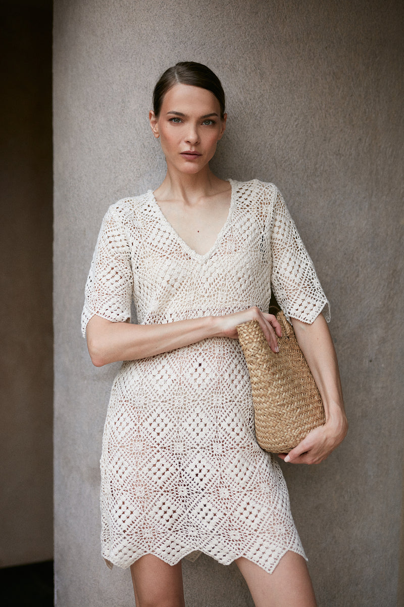 A model wearing a creme cotton lace mini dress