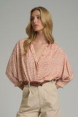 A woman wearing a tangerine and ivory top for winter