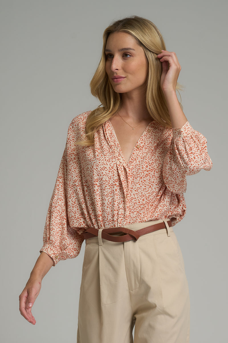 A woman wearing a casual orange floral print top