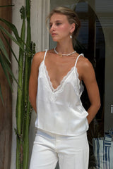 Model wears white tie shoulder satin cami for day to night styling.