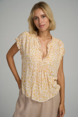 A model wearing a casual yellow floral blouse