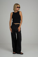 A woman wearing high rise black linen pants