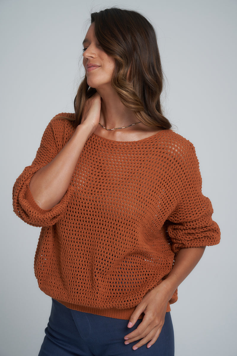 A model wearing a rust coloured cotton knit top