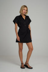 A model wearing a black cotton mini wrap dress