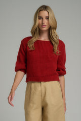 A woman wearing a cropped red knit jumper
